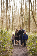 Fototapeta premium Family with pet dog walking in a wood, vertical