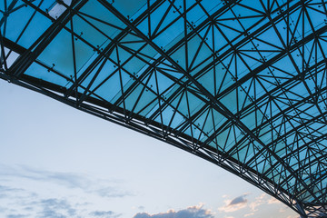 Bottom view of modern glass roof in business district in evening light at sunset with copyspace