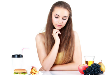 Young doubting girl with apple and hamburger isolated