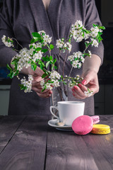 Cup of coffee and cherry blossom branch on a dark background