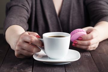 Coffee and macaron cookies on table in the morning, female hand