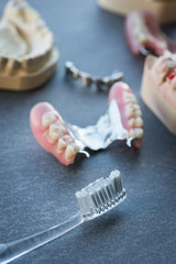 Artificial replacement teeth with tooth brush on a dark table