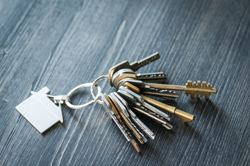 Bunch of keys with house shaped key ring on a wooden table