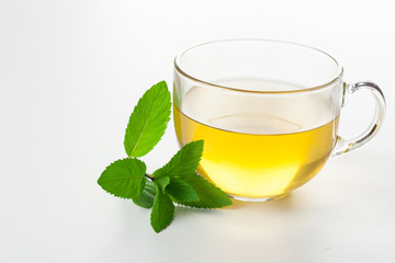 Glass of mint tea on white mint leaves on the side