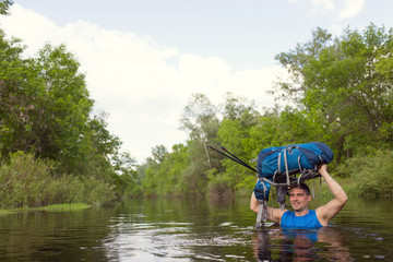 Man crossing the river with a backpack.