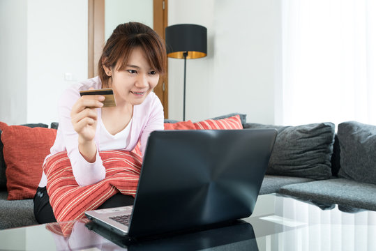 Asian young woman sitting on couch shopping online at home