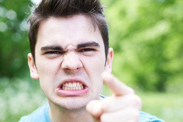 Outdoor Head And Shoulders Portrait Of Angry Young Man