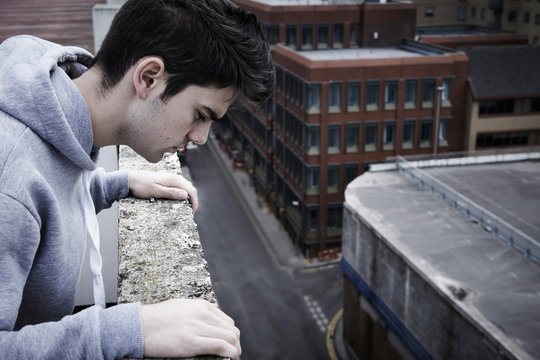 Depressed Young Man Contemplating Suicide On Top Of Tall Buildin