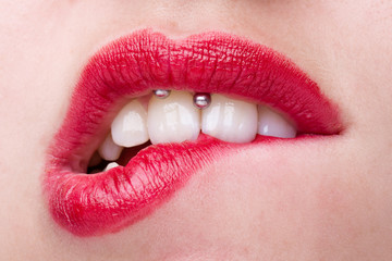 Naklejka premium Kobieta z Smiley piercing gryzie jej usta czerwoną szminką