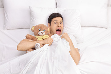 Terrified young man laying in bed