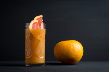 Grapefruit beverage on the black wooden background