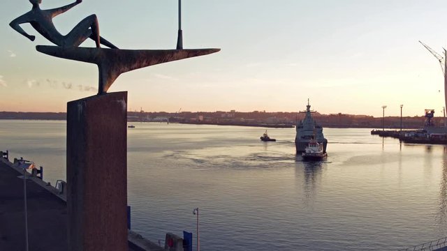Der Segler im Sonnenaufgang von Kiel mit Marine Schiff im Hintergrund
