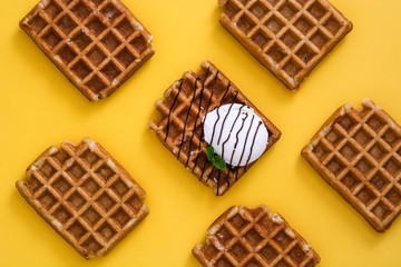 Waffles with chocolate sauce, ice cream and mint on yellow background
