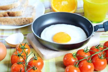 Fried egg, toast bread, fresh juice, tomatoes and oranges