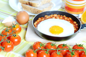 Fried egg with beans, toast bread, fresh juice, tomatoes and oranges