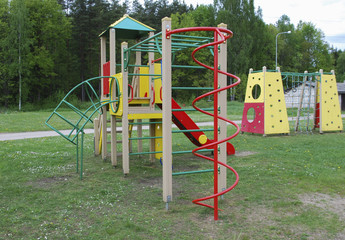 Children’s multi colors playground in public park. Hanging rope, bridge, stairs, slide, platforms. Place for games and sports activities.