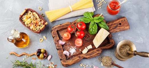Italian food background with vine tomatoes, basil, spaghetti, olives, parmesan, olive oil, garlic