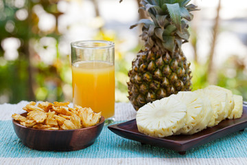 Glass of pineapple smoothie, juice with dried dehydrated deep fried pineapple chips and fresh fruit