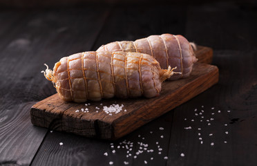 Raw Chicken roll with salt on a wooden board