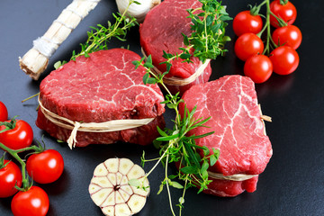 Fresh Raw Beef steak Mignon, with salt, peppercorns, thyme, tomatoes.