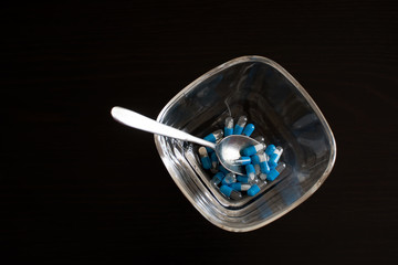 bowl with spoon and medicine in capsules