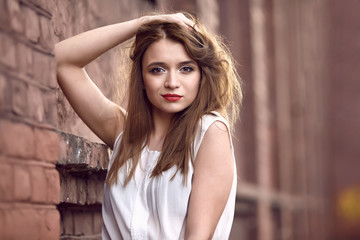 Fototapeta premium young woman near a brick wall. Fashion concept. City lifestyle. Female fashion. Closeup portrait 