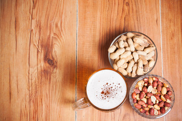 Beer background. Beer with peanuts on the brown wooden table. Fr