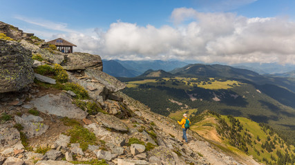 Hiker follows the trail towards Mount Rainier. Amazing view at the mountains which rose against the cloud sky.  MOUNT FREMONT LOOKOUT TRAIL, Sunrise Area, Mount Rainier