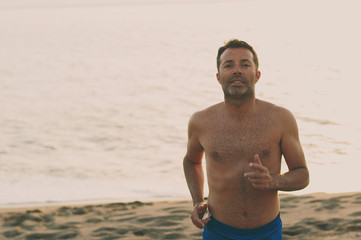 Handsome fit man running on the sunset beach