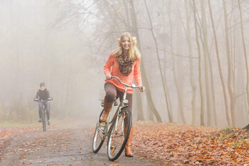 Happy active woman riding bike in autumn park.