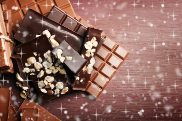 Variety of chocolate pieces on wooden background with snow effect