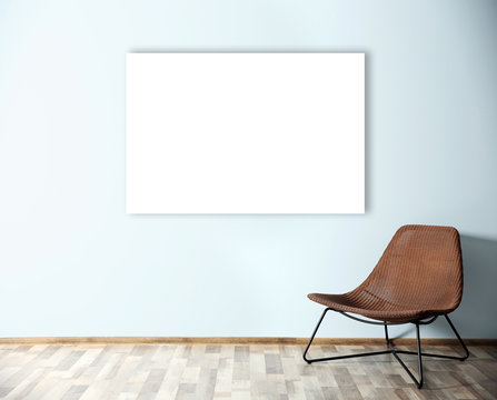 Comfortable chair and empty picture frame on blue wall background