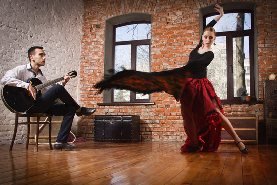 Young woman dancing flamenco and a man playing the guitar