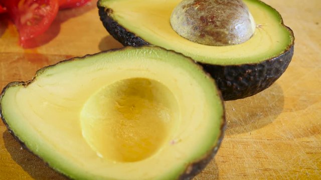 Perfect ripe Haas avocado cut in half on a cutting board - dolly shot