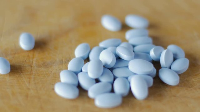 Close up of blue pills spinning on a wooden board