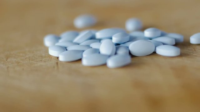 Blue pills rotating on a piece of wood shot from a low angle