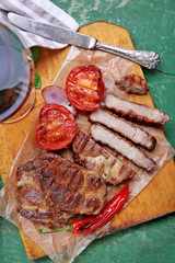 Roasted beef fillet and vegetables on cutting board, on wooden background