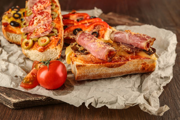 Hot pizza baguette with bacon and cheese on wooden table