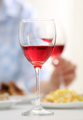 Dinner with glasses of wine on light blurred background