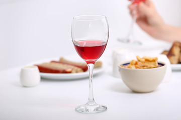 Dinner with glasses of wine on light blurred background