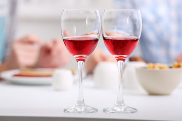 Dinner with glasses of wine on light blurred background