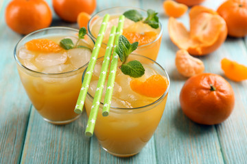 Fresh cocktails with ice, mint and tangerines on the wooden table, close up