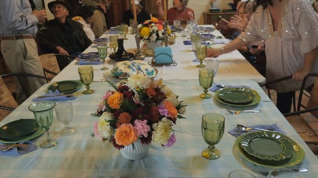 Pan up of a large table as guests arrive to a passover seder
