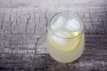 Glass of lemon soda with ice on rustic wooden background