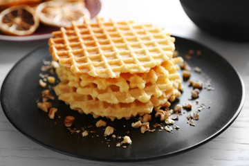 Fresh waffles with honey and dried oranges on wooden background