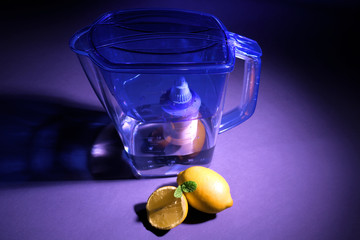Water filter jug and lemons on dark background