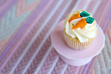 Cupcake with frosting and decorative carrots on cloth background
