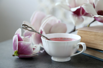 Cup of tea with books and flowers on table