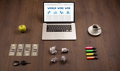 Laptop on wooden desk with office suplies