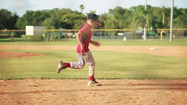 Slow motion of kid running to first base during baseball practice